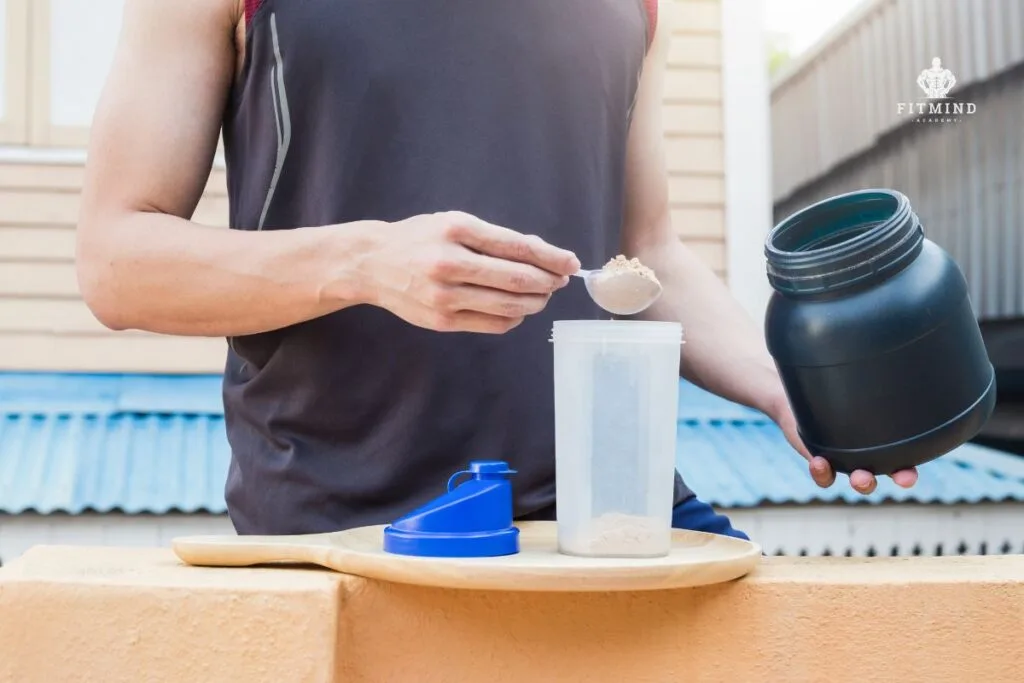 proteína whey en polvo junto a un shaker y alimentos ricos en proteína